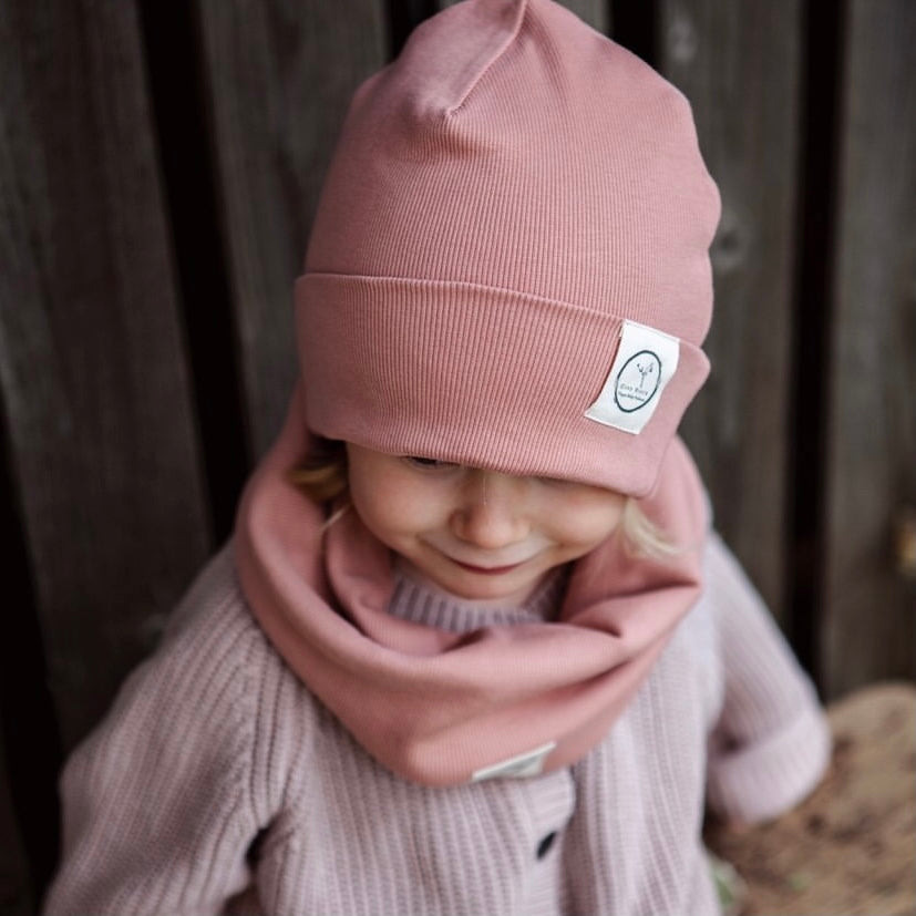 Kuschelig weiche Beanie aus GOTS-zertifizierter Bio-Baumwolle in unserer exklusiven Farbe Dusty Rose.  Die Beanie ist aus fein geripptem und sehr elastischem Stoff, sodass die Mütze mit wächst und Ihr lange Freude daran haben werdet.  Kreiere perfekte Looks indem Du die Beanie mit unseren Schühchen, Leggings und Schals kombinierst!